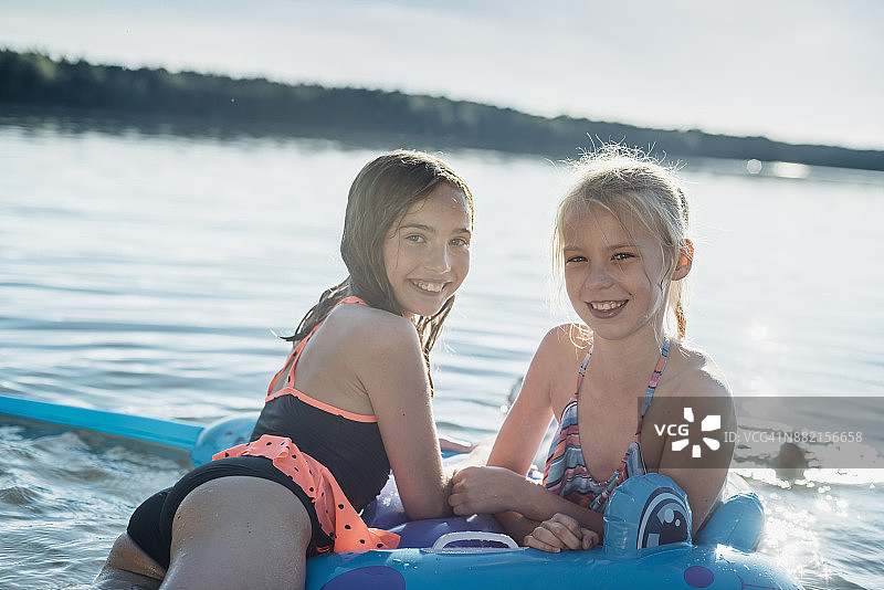 两个女孩带着游泳玩具在湖边的肖像图片素材