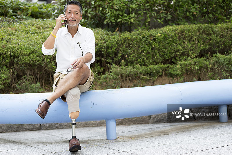 一名日本男子戴着假肢坐在他的办公室外面，用手机打电话图片素材