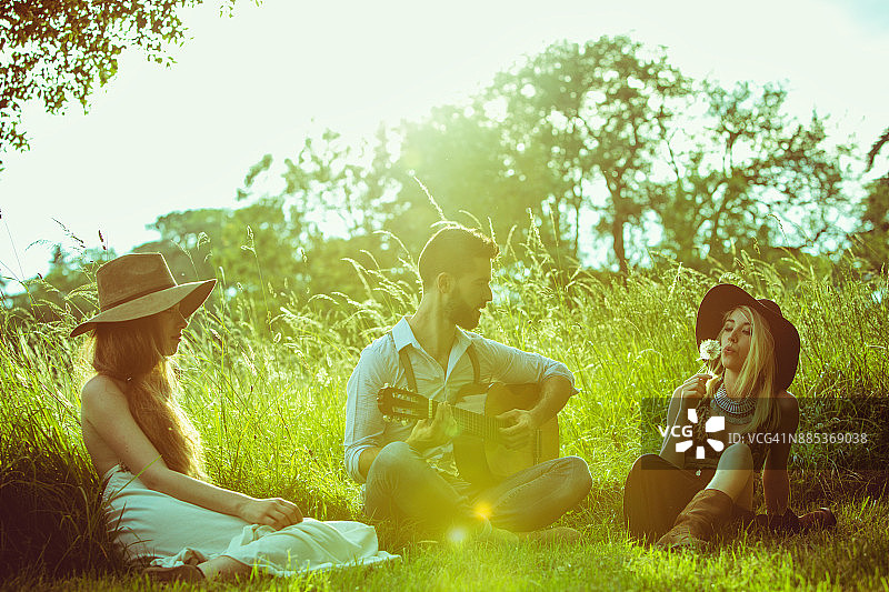 一群年轻的潮人坐在草地上，弹吉他图片素材