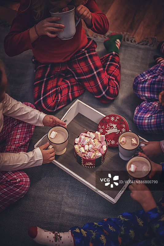 穿着睡衣和圣诞袜的可爱的孩子们在圣诞节喝着热巧克力和棉花糖图片素材