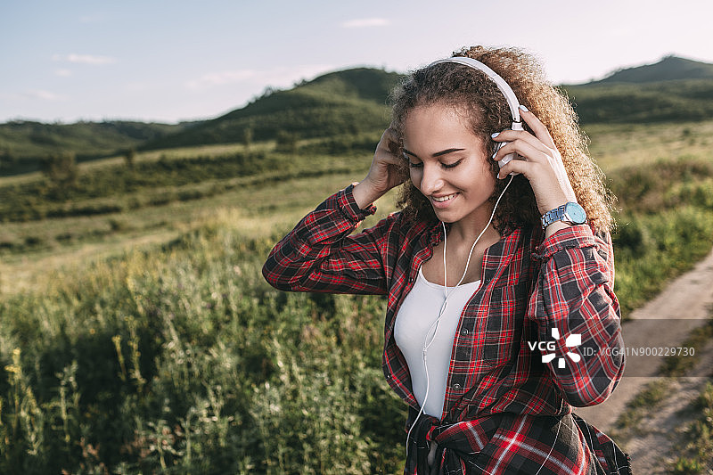 十几岁的女孩戴着耳机在大自然中听音乐图片素材