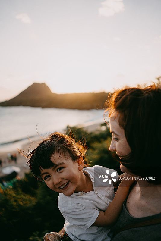 可爱的蹒跚学步的小女孩和她的妈妈在夕阳下笑图片素材