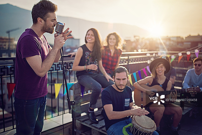 一群朋友在屋顶平台上举行音乐会庆祝图片素材