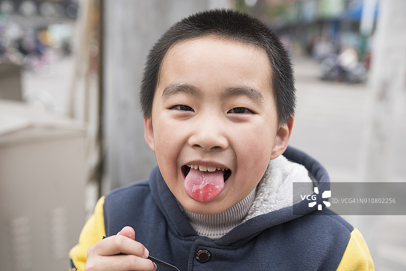 亚洲小学男孩吃果酱在街上高兴图片素材