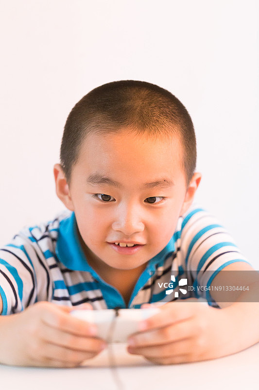 亚洲男孩与玩把手在桌子上看着相机图片素材