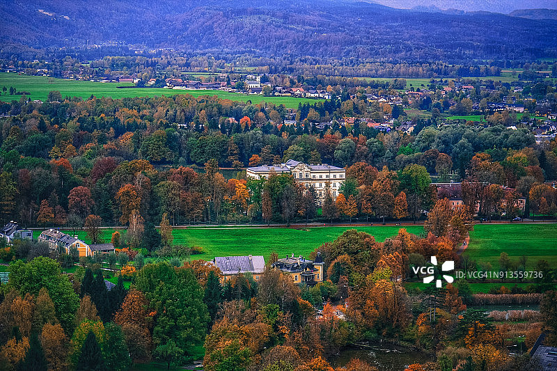 秋天，从空中俯瞰奥地利萨尔茨堡城堡屋顶上的绿色田野中央的当地房屋图片素材
