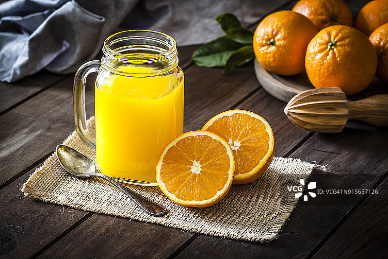 在粗糙的木桌上拍摄的橙汁玻璃罐图片素材