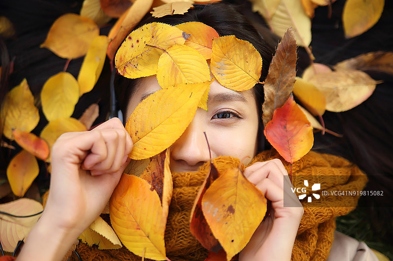 微笑的女人躺在秋叶上图片素材