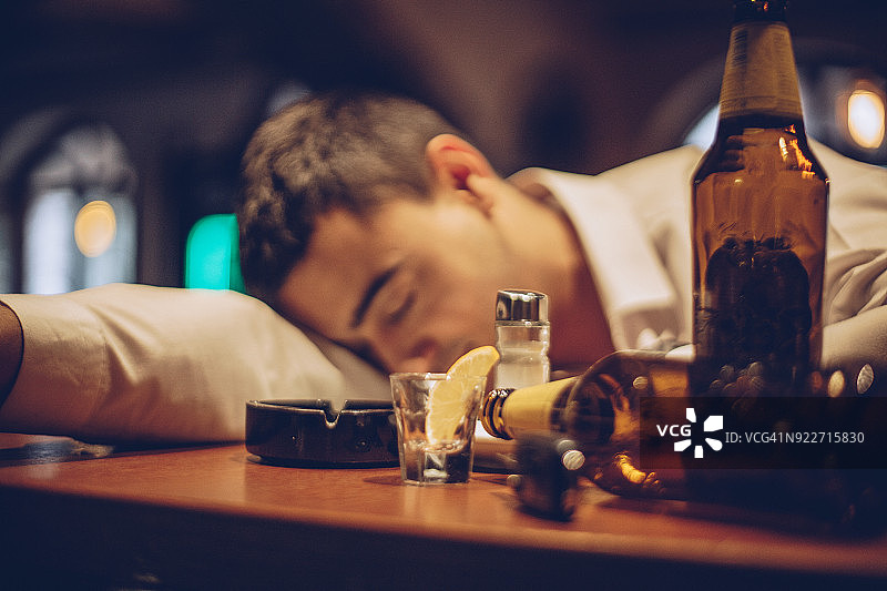 一个年轻的醉汉睡在吧台上图片素材