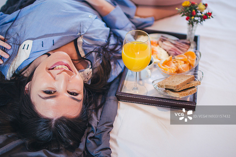 幸福的女人在床上吃早餐图片素材