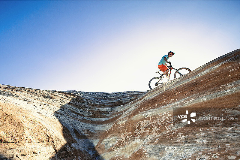 一个男人骑着山地车在一个极端的砂岩岩架上图片素材