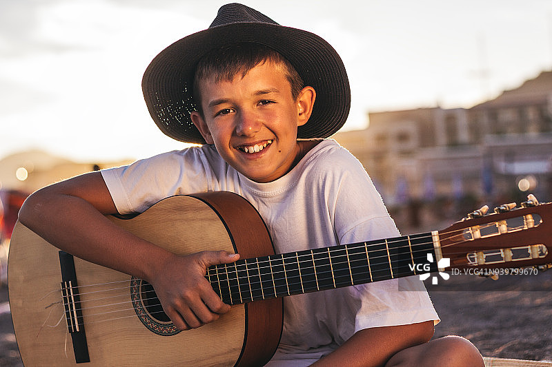 可爱的男孩在海滩上弹吉他图片素材