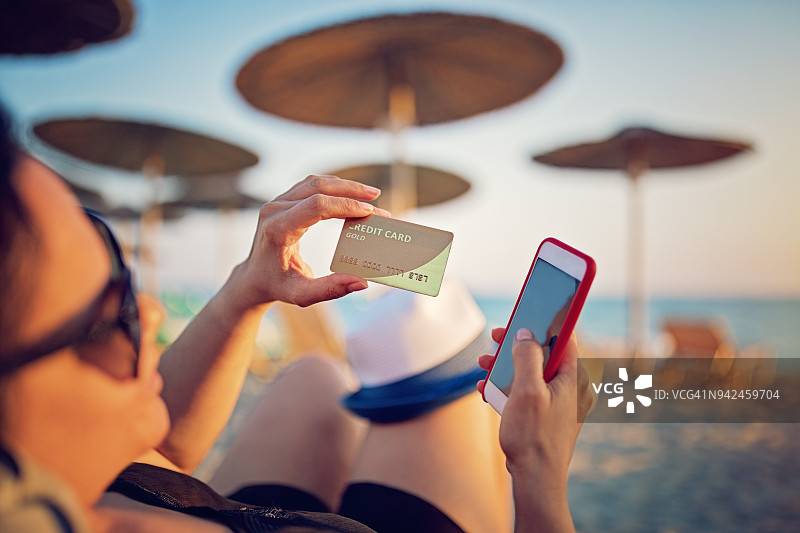 一个女人在海滩上用信用卡网上购物图片素材