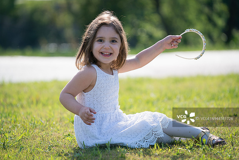 快乐的小女孩坐在草地上图片素材