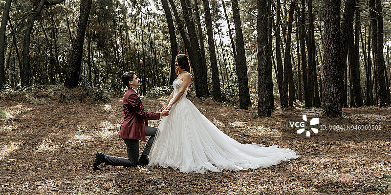一个男人在森林里跪着向幸福的新娘求婚图片素材
