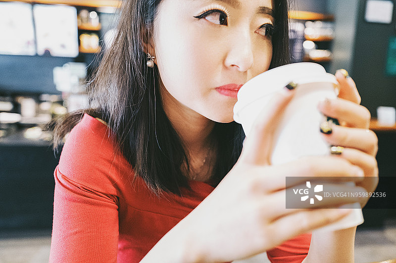 一位美丽的女孩在中国云南省昆明市的一家咖啡店里喝咖啡。图片素材
