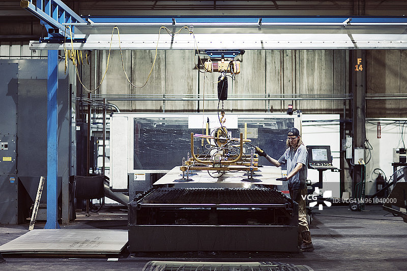 在工业上使用机械钢板的工人的全身长度图片素材