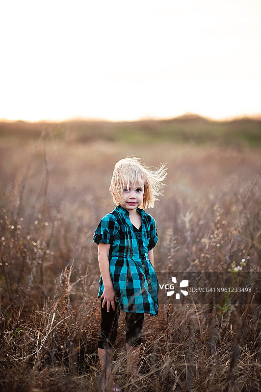 女孩的肖像站在草地上与植物对抗晴朗的天空图片素材