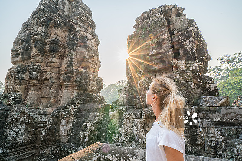 年轻女子凝视着柬埔寨古老的寺庙巴戎寺，吴哥窟建筑群图片素材