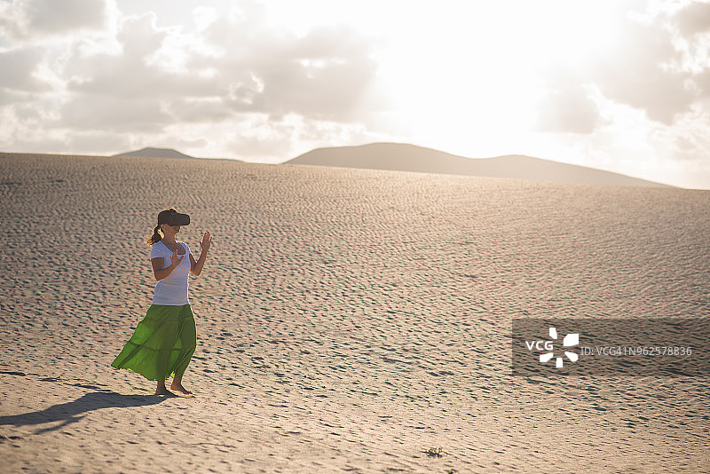 沙漠里戴着虚拟现实眼镜的女人图片素材