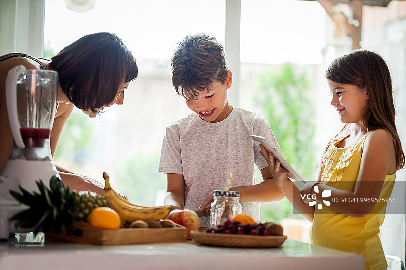 女人和她的孩子在厨房切水果图片素材