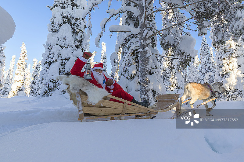 圣诞老人坐在驯鹿雪橇上。芬兰拉普兰北部的鲁卡(库萨莫)地区图片素材