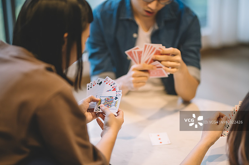 亚洲中国朋友在客厅玩扑克游戏图片素材