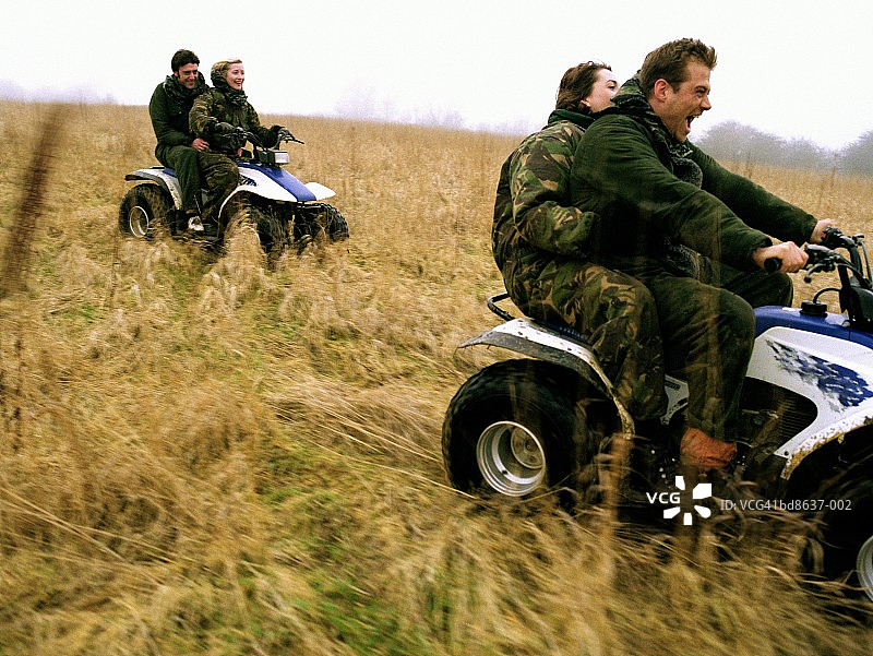 两对夫妇骑着四轮摩托车穿过田野图片素材