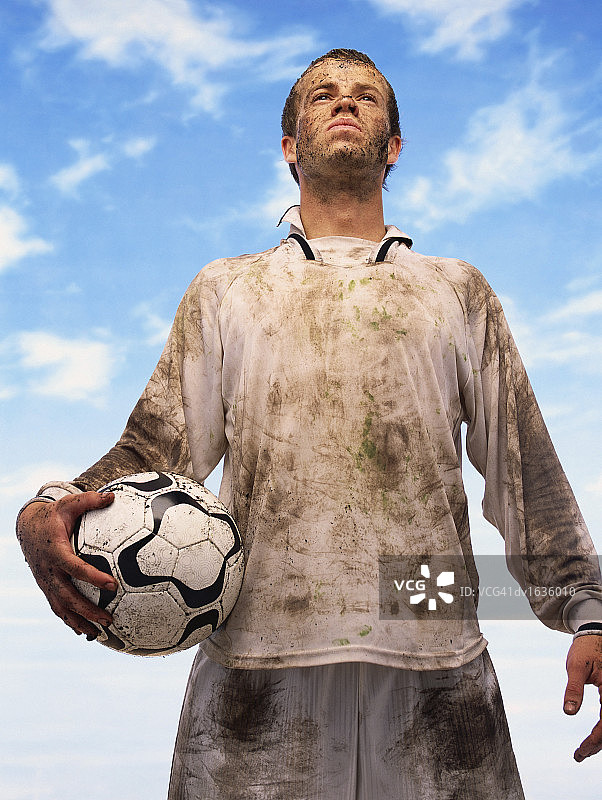 低角度的一个出汗的足球运动员覆盖在泥图片素材