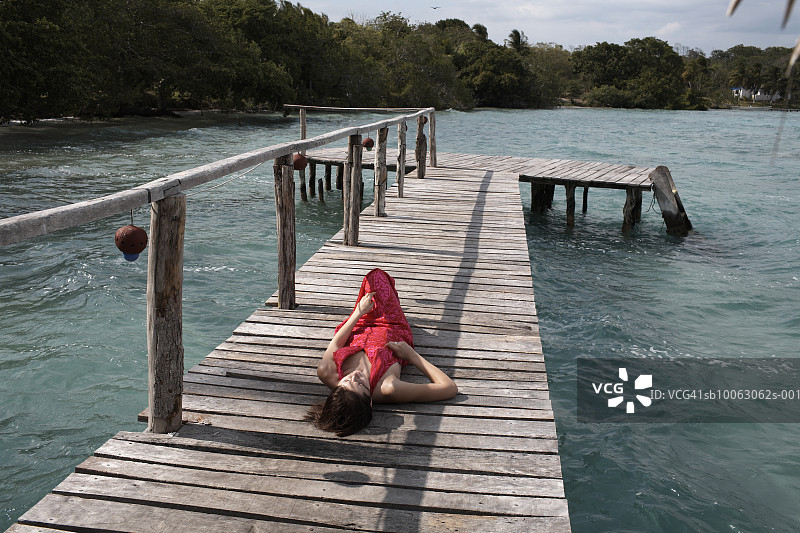 年轻女子躺在防波堤上，居高临下图片素材