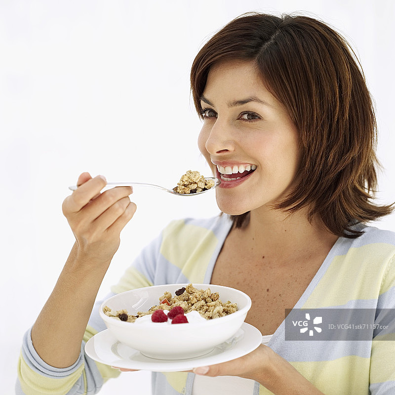 一个女人在吃一碗麦片的侧视图图片素材