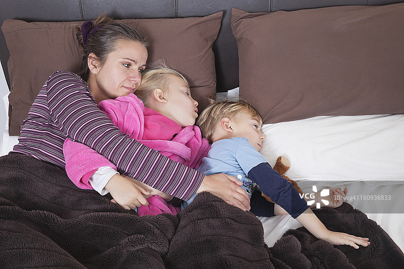 母亲带着两个孩子躺在床上图片素材