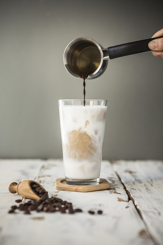 在冰牛奶中倒咖啡的特写图片素材