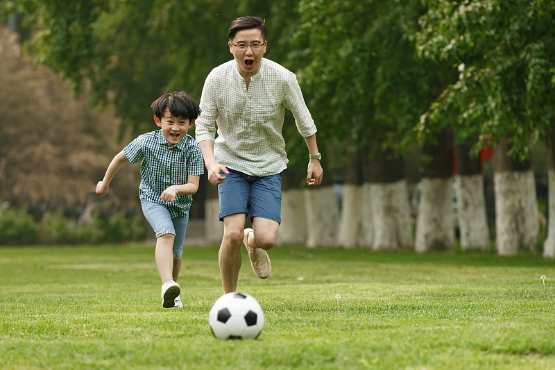 快乐父子在草地上踢足球图片素材