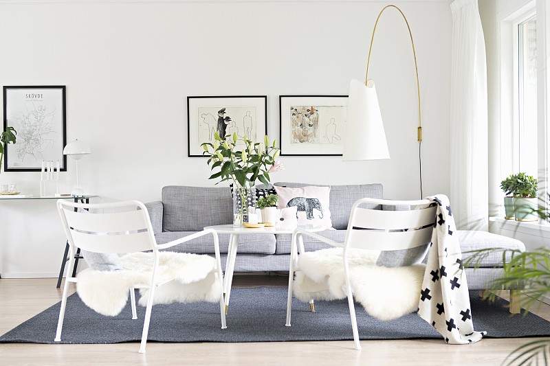 白色花园椅上的羊皮，浅灰色沙发和休息区的设计师标准灯图片下载