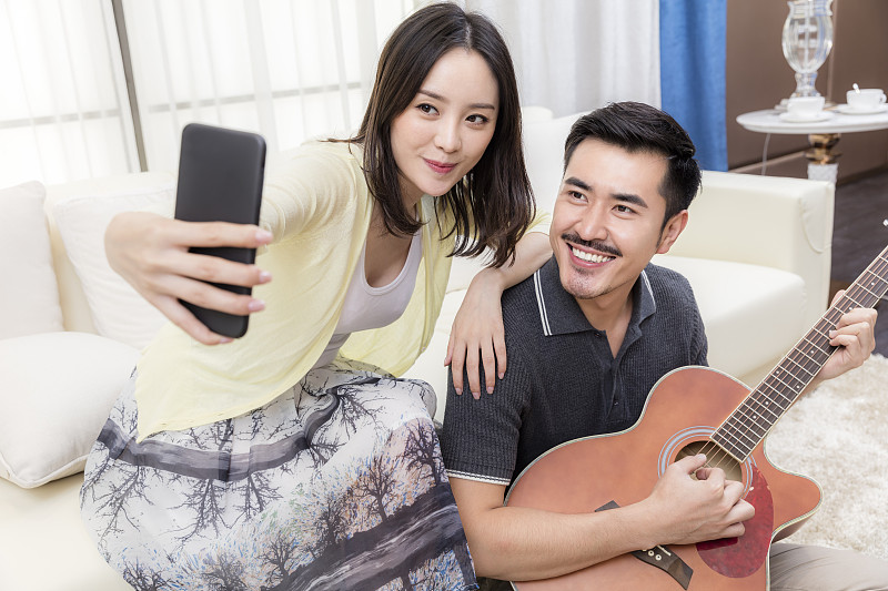 年轻的夫妻在客厅弹吉他图片素材