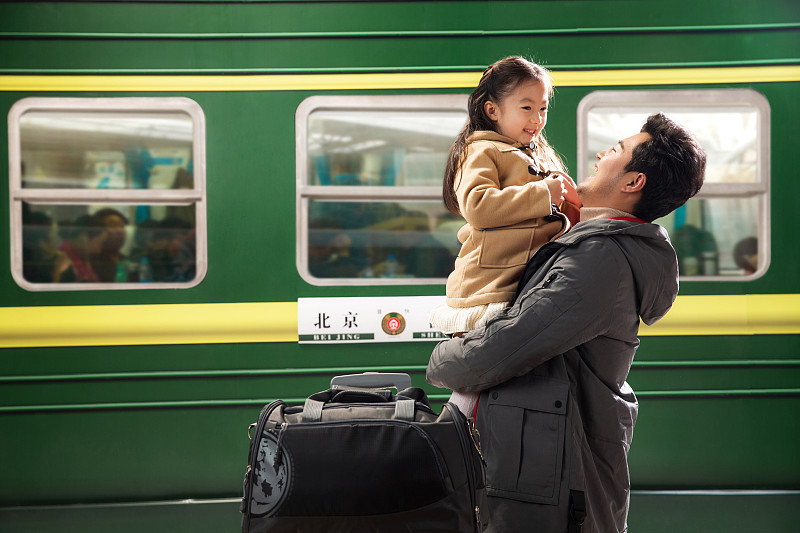 父亲抱着女儿站在火车站站台上图片下载