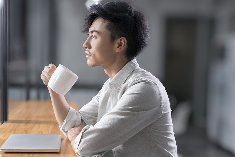 Creative businessman drinking coffee in break room图片下载