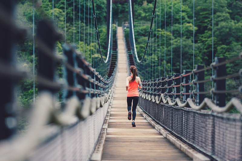在桥边慢跑的女运动员图片素材