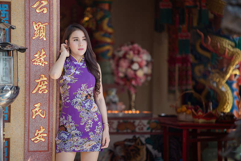 中国妇女穿着传统旗袍站在中国寺庙。图片素材