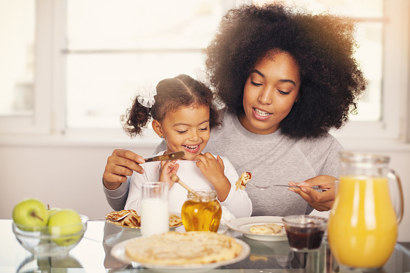 非裔美国人年轻的母亲和女儿正在吃早餐图片下载