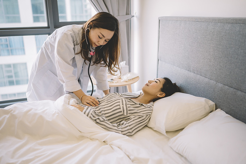 一名亚裔华裔女医生在一名中国女病人家访期间为她做检查图片素材