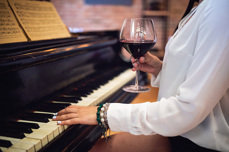 年轻的女钢琴家喜欢演奏和喝酒图片素材