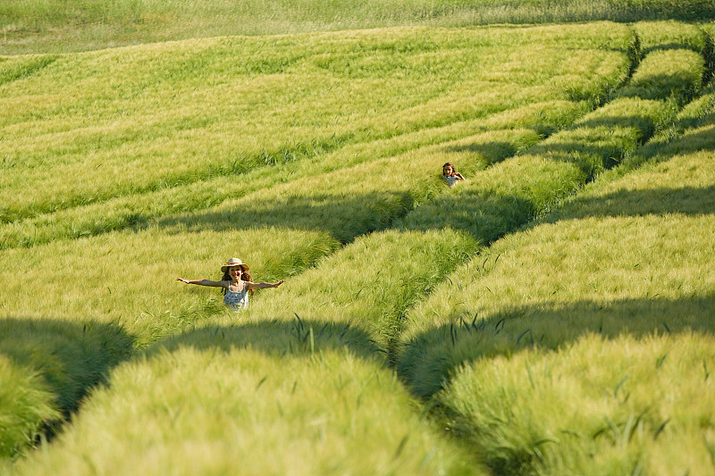 无忧无虑的姑娘们在阳光明媚、田园诗般的绿色农村麦田里奔跑图片素材