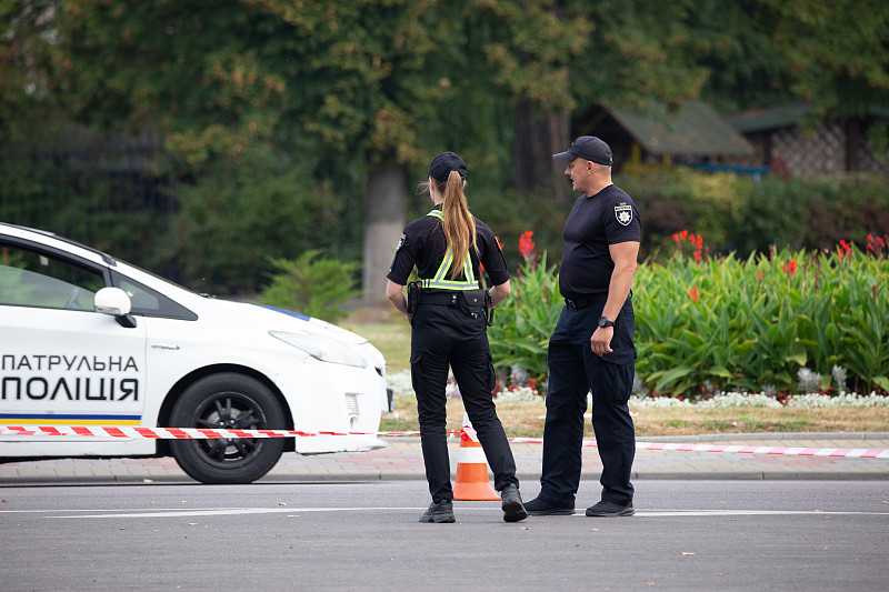 女警察和男警察在封闭的道路前面巡逻警车过马路附近。图片下载