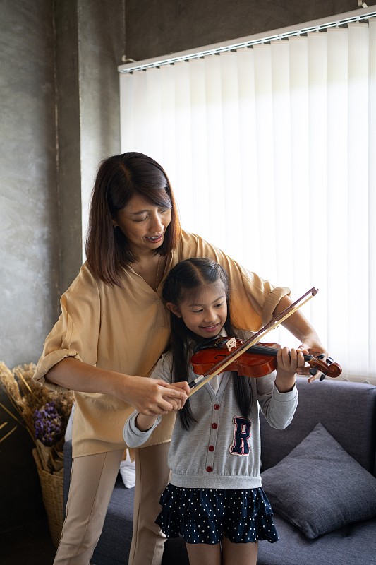 亚洲妇女教小提琴和一个小女孩。图片下载