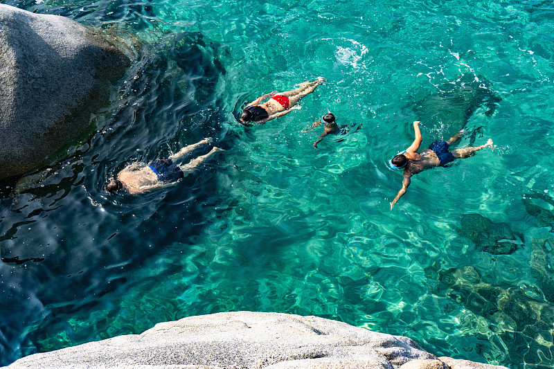 Family of four swimming in crystal clear sea, Cagliari, Sardinia图片素材