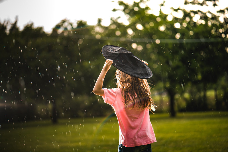 背影小女孩试图保护自己不被雨淋湿图片下载