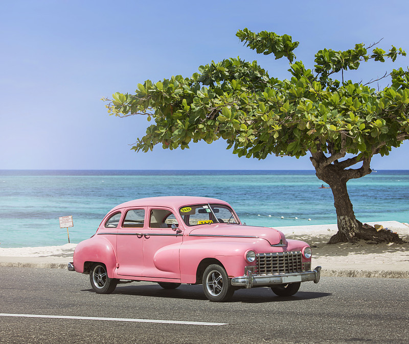在古巴哈瓦那附近的海滩上，老式的经典粉色美国老爷车图片下载