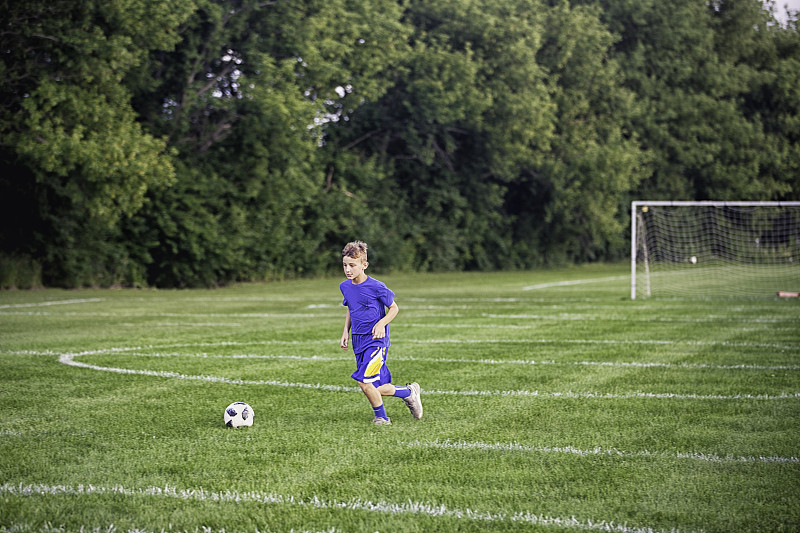 11岁的男孩在足球场上运球图片下载